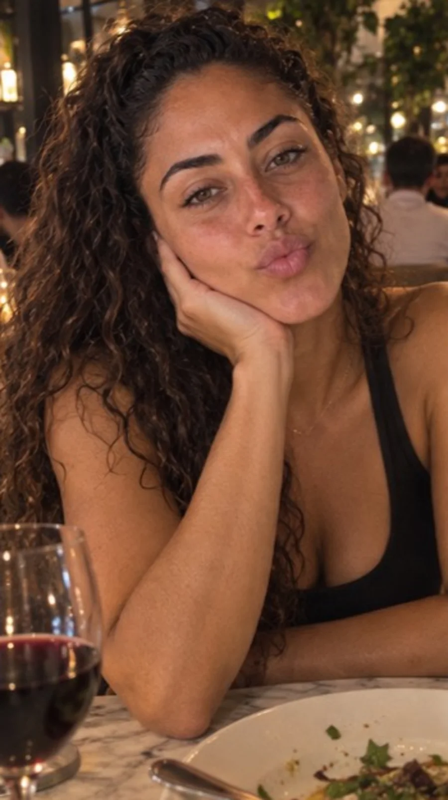 Camila resting her face on her hand at dinner